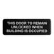 A black Tablecraft sign with white text that says "This door to remain unlocked when building is occupied"