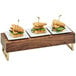 A row of waffle sandwiches on a walnut wood and brass display riser.