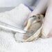 A person in gloves using a Mercer Culinary Boston Style Oyster Knife to open an oyster.