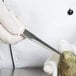 A gloved hand uses a Dexter Russell 4" oyster knife to shuck an oyster.