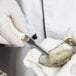 A person using a Dexter Russell Boston Style Oyster Knife to cut an oyster.
