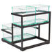 A glass container on a black metal stand with three trays.