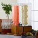 A Cal-Mil Madera beverage dispenser with infusion chamber filled with fruit.
