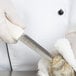 A gloved hand uses a Dexter Russell oyster knife with a white textured handle to open an oyster.