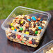 A Fabri-Kal Greenware plastic deli container filled with nuts and candies.
