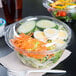 A Dart plastic bowl filled with salad and a fork and knife.