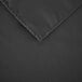 A close up of a black square polyester table cover with a hemmed edge.