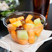 A Dart plastic deli container filled with fruit on a counter.