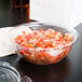 A Dart plastic bowl of salsa with a flat lid on a table.