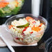 A Dart plastic bowl of pasta and vegetables with a SafeSeal lid on a counter.