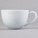 A close-up of a Tuxton white porcelain cappuccino cup with a handle.