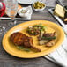 A GET Tropical Yellow oval melamine platter with food on a table.