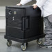 A person pushing a black trolley with a large container.