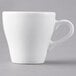 A close-up of a Tuxton white porcelain espresso cup with a handle.