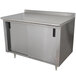 A stainless steel Advance Tabco work table with cabinet base and mid shelf and a backsplash.