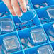 A hand placing a glass in a blue Carlisle tilted cup rack.