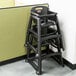 A black Rubbermaid high chair leaning against a wall.