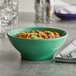 A Tuxton cilantro green bowl filled with food on a table.