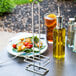 A Tablecraft chrome metal holder on a table with a bottle of olive oil.