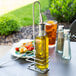 A Tablecraft metal holder with a bottle of olive oil on a table.