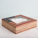 A 9" x 9" x 2 1/2" bakery box with a window and vintage American flag design on the counter.