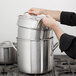 A person holding a large pot over a stove.