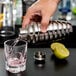 A person using a Vollrath stainless steel cobbler cocktail shaker to pour a drink.