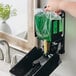 A person holding a bag of green Kutol lotion soap over a bathroom sink.