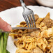 A clear plastic fork and pasta on a plate.