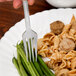 A WNA Comet Reflections plastic fork holding meat and green beans on a plate.