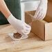 A person wearing gloves using Western Plastics perforated plastic wrap to pack food in a box.