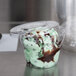 A close-up of a WNA Comet clear plastic lid on a plastic dessert container with green ice cream inside.