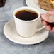 A person holding a Homer Laughlin ivory narrow rim saucer with a cup of coffee.