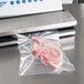 A piece of meat being vacuum sealed in a Vollrath external strip vacuum packaging machine.