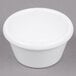 A close-up of a white Carlisle ramekin on a gray surface.
