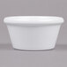 A close-up of a white Carlisle ramekin on a gray surface.