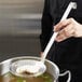 A person using a Vollrath Jacob's Pride skimmer to remove food from a pot.