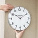 A person hanging a Taylor large dial clock on a wall.