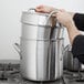 A man using a Vollrath Classic stainless steel double boiler pot on a stove.