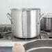 A person using a Vollrath stainless steel stock pot as a double boiler.