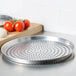 An American Metalcraft aluminum pizza pan with perforated holes filled with tomatoes on a vine.