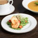 A 10 Strawberry Street Gold Line porcelain salad plate with food on a table.