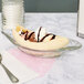 A banana split in a Libbey glass bowl with chocolate syrup and whipped cream.