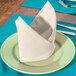 An ivory Intedge cloth napkin folded on a plate with silverware.