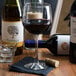 A Libbey Vina balloon wine glass filled with red wine next to wine bottles.