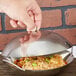 A hand using a Thunder Group stainless steel wok cover to cover a bowl of rice.