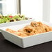 An American Metalcraft rectangular melamine serving bowl with food on a table.