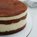 An 18" white corrugated cake circle with a chocolate and cream cake on top.
