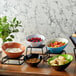 A table with black slanted melamine bowls of food, including fruit, salad, and cereal.