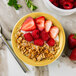 A Tuxton saffron china monkey dish filled with granola and strawberries.